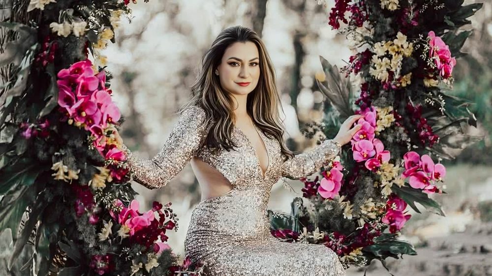 Mulher elegante sentada em balanço decorado com flores, representando a positividade e prosperidade.