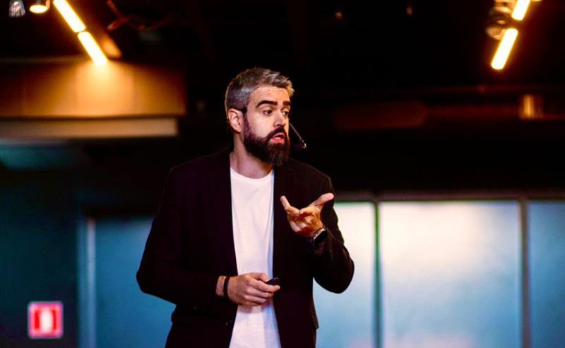 Palestrante gesticulando com intensidade durante apresentação sobre feedbacks produtivos e comunicação em tempos difíceis.